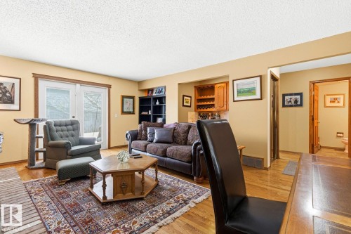 Living area featuring wood-finish flooring, light tan walls, and built-in cabinetry with a wine rack - 11707 29 Avenue Nw, Edmonton, AB - Indoor Photo Showing Living Room
