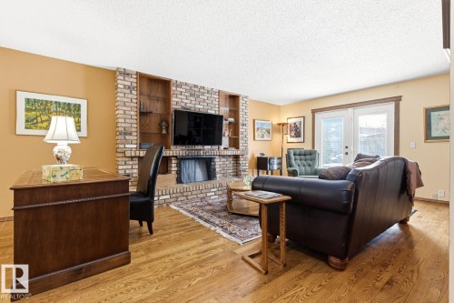Living area featuring wood-finish flooring and a brick fireplace - 11707 29 Avenue Nw, Edmonton, AB - Indoor Photo Showing Living Room