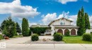 Stucco exterior featuring an arched window with balcony, integrated garage with arched entries, and a front entrance partially covered by established climbing greenery - 11707 29 Avenue Nw, Edmonton, AB  - Outdoor 