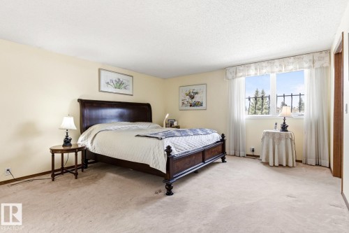 Spacious bedroom featuring light-toned carpeting, a textured ceiling, and pale yellow wall finishes - 11707 29 Avenue Nw, Edmonton, AB - Indoor Photo Showing Bedroom