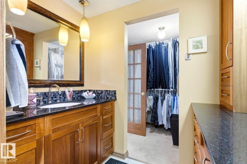 Bathroom vanity featuring a dark countertop, white oval sink, and chrome faucet - 11707 29 Avenue Nw, Edmonton, AB - Indoor Photo Showing Bathroom