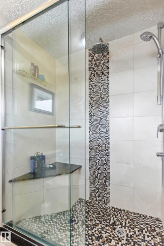 Glass-enclosed shower featuring a rain shower head, hand-held shower fixture, and a mosaic tile accent strip - 11707 29 Avenue Nw, Edmonton, AB - Indoor Photo Showing Bathroom