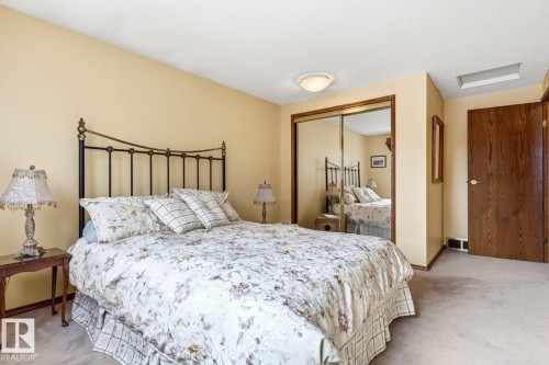 Bedroom featuring a mirrored closet, wood-finish door, and light-colored carpeting - 11707 29 Avenue Nw, Edmonton, AB - Indoor Photo Showing Bedroom