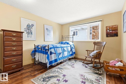 Bedroom featuring wood-finish flooring, light-toned walls, and a large window with white trim - 11707 29 Avenue Nw, Edmonton, AB - Indoor Photo Showing Bedroom