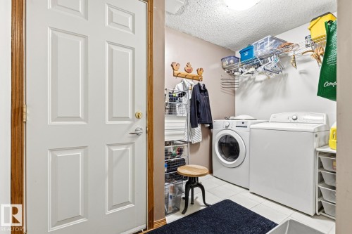 Dedicated laundry area featuring a front-load washing machine, top-load washing machine, and wall-mounted shelving for storage - 11707 29 Avenue Nw, Edmonton, AB - Indoor Photo Showing Laundry Room
