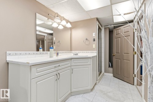 Bathroom featuring white cabinetry, a white countertop, and a vanity mirror with sconce lighting - 11707 29 Avenue Nw, Edmonton, AB - Indoor Photo Showing Laundry Room