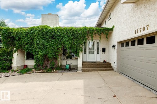 Inviting front entrance with a white door, a multi-pane garage door, stucco exterior, and a prominent address number - 11707 29 Avenue Nw, Edmonton, AB - Outdoor