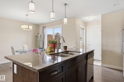 The kitchen features a dark wood island with a granite countertop and a stainless steel double sink - 