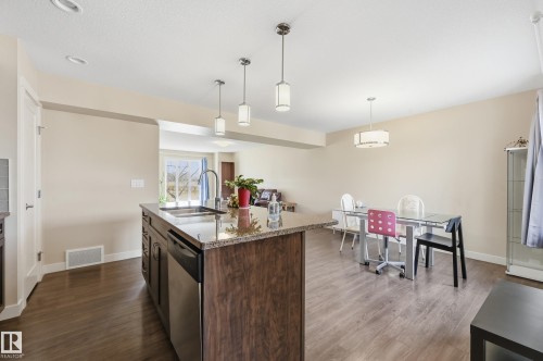 Kitchen featuring a center island with a granite countertop, a stainless steel sink, and a dishwasher - 701 Allard Boulevard, Edmonton, AB - Indoor