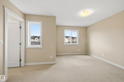 This room features neutral-toned carpet, light beige walls, and two windows providing natural light - 