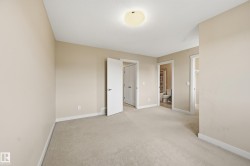 Spacious room featuring neutral carpeting, a ceiling-mounted light fixture, and access to an adjoining bathroom - 