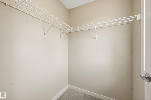 The property features a walk-in closet with wire shelving and gray carpet flooring - 701 Allard Boulevard, Edmonton, AB - Indoor With Storage