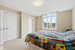 Bedroom featuring beige walls, light-colored carpet, and a large window providing natural light - 