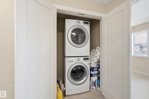 Dedicated laundry area featuring a stacked washer and dryer unit, conveniently located within a closet with bi-fold doors - 701 Allard Boulevard, Edmonton, AB - Indoor Photo Showing Laundry Room