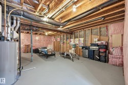 Spacious unfinished basement with exposed wooden beams, a water heater, and insulation visible on the walls - 