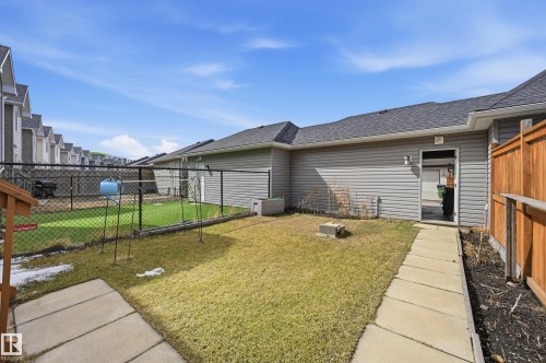 The property features a fenced yard with a lawn, a paved walkway, and a back entrance - 701 Allard Boulevard, Edmonton, AB - Outdoor With Exterior