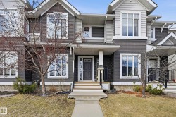 The property features a dark gray and light gray exterior siding, with white trim around the windows and eaves - 