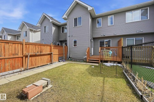 The property features a private yard with a lawn, a wooden fence, and a deck with steps leading to the yard - 701 Allard Boulevard, Edmonton, AB - Outdoor With Deck Patio Veranda With Exterior