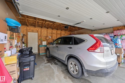 The garage features an overhead door, exposed wooden studs, and a side door for convenient access - 701 Allard Boulevard, Edmonton, AB - Indoor Photo Showing Garage