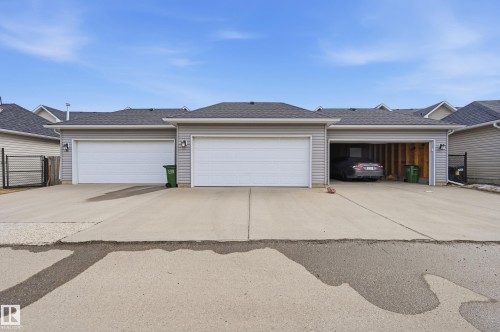The property features a multi-car garage with overhead doors and a concrete driveway - 701 Allard Boulevard, Edmonton, AB - Outdoor