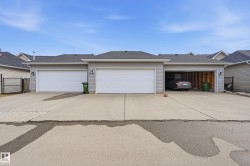 The property features a multi-car garage with overhead doors and a concrete driveway - 