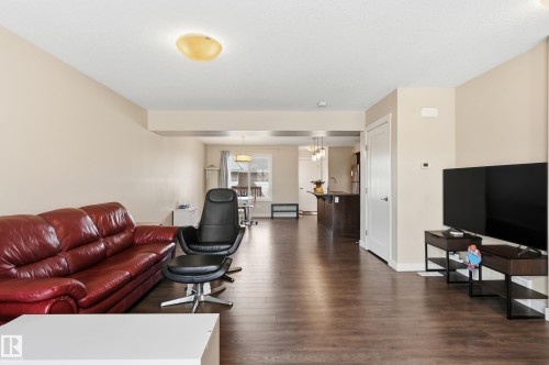 The main living area features wood-look flooring and light-toned walls, extending into the dining area and kitchen - 701 Allard Boulevard, Edmonton, AB - Indoor Photo Showing Living Room