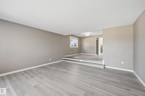 The expansive living area features light-toned flooring, neutral wall paint, and a multi-level design - 6907 19 Avenue, Edmonton, AB - Indoor Photo Showing Other Room