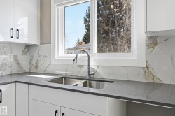 Kitchen featuring white cabinetry, a double basin stainless steel sink, a modern faucet, and a tiled backsplash - 