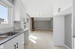 The kitchen features sleek white cabinetry, a double basin sink, and a countertop with an integrated backsplash - 