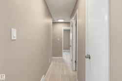 The property features a hallway with light-toned flooring, neutral wall paint, and white trim - 