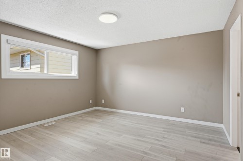 This room features light-colored laminate flooring, neutral-toned walls, and a window providing natural light - 6907 19 Avenue, Edmonton, AB - Indoor Photo Showing Other Room