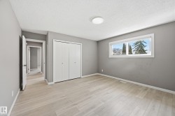 This room features light-colored flooring, a window offering views of trees and sky, and a white bi-fold closet - 