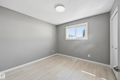 This room features light-colored flooring, a window offering natural light and views of trees and sky, and a contemporary ceiling light fixture - 6907 19 Avenue, Edmonton, AB - Indoor Photo Showing Other Room