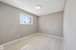 This room features light-colored flooring, a window with white trim, and a ceiling light fixture - 