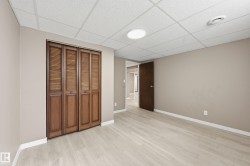This room features light-toned flooring, a neutral wall color, and a dark wood bifold closet door - 