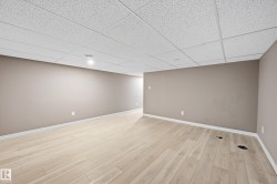 Expansive room featuring light-colored flooring, neutral-toned walls, and a drop ceiling with integrated lighting - 