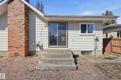 The property features a brick chimney, exterior siding, and a patio area with brick paving - 