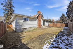 The property features a spacious yard with a wooden fence and a visible brick chimney - 