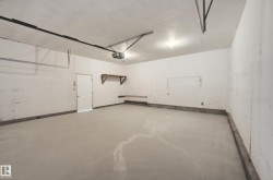 Spacious garage featuring concrete flooring, white walls, and overhead lighting - 