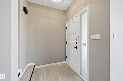 Entryway featuring a paneled door with black hardware, an adjacent sidelite, light-colored walls, and a ceiling light fixture - 6907 19 Avenue, Edmonton, AB - Indoor Photo Showing Other Room