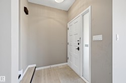 Entryway featuring a paneled door with black hardware, an adjacent sidelite, light-colored walls, and a ceiling light fixture - 