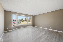 This spacious room features light wood-style flooring and a large bay window, providing ample natural light and views of the surrounding neighborhood - 