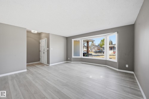 This inviting living space features light-colored flooring, neutral gray walls, and white baseboards - 6907 19 Avenue, Edmonton, AB - Indoor Photo Showing Living Room
