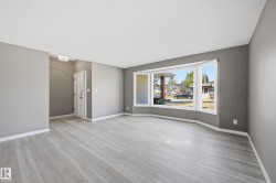 This inviting living space features light-colored flooring, neutral gray walls, and white baseboards - 