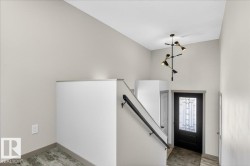 Entryway featuring high ceilings, a decorative chandelier, and a black paneled door with leaded glass - 