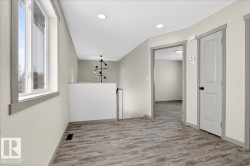 Open landing area featuring wood-finish flooring, recessed lighting, and a contemporary light fixture - 