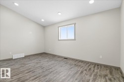 Interior room featuring light gray walls, wood-finish flooring, a double-pane window, recessed lighting, and dark baseboards - 