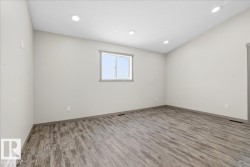 Spacious room featuring wood-finish flooring, light neutral wall tones, and recessed lighting - 