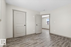 Room featuring wood-finish flooring, light grey walls, white ceilings, and two paneled doors with black hardware - 