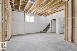 Unfinished basement space with a concrete floor, exposed wood ceiling joists, and a horizontal sliding window - 
